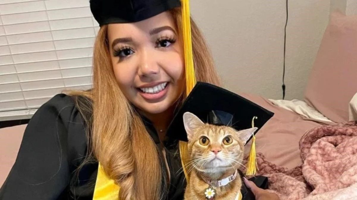 A woman and a ginger cat in a matching cap and gown.