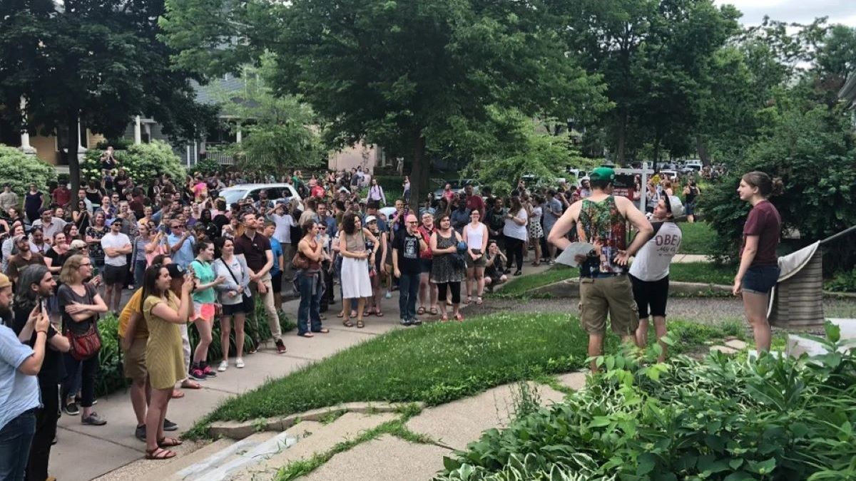 A large group of people gathered outside a home.